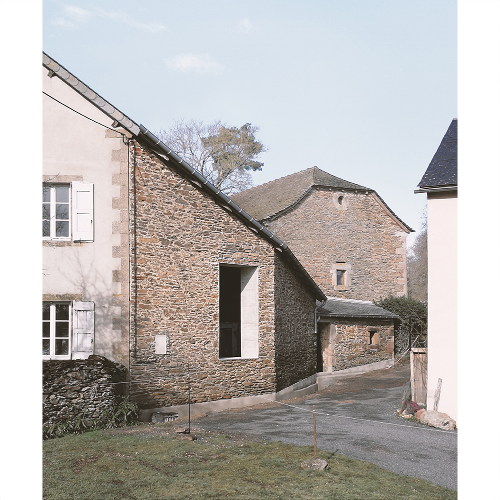 Ouverture contemporaine en béton dans un mur en pierre