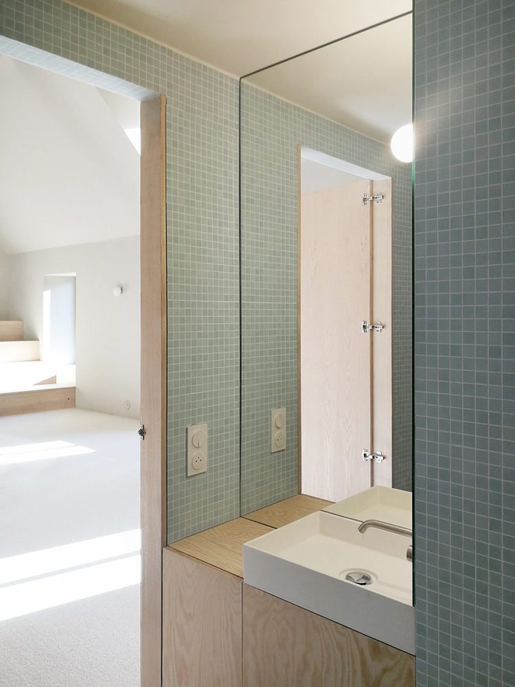 Salle de bain chalereuse avec murs en mosaique et mobilier bois 