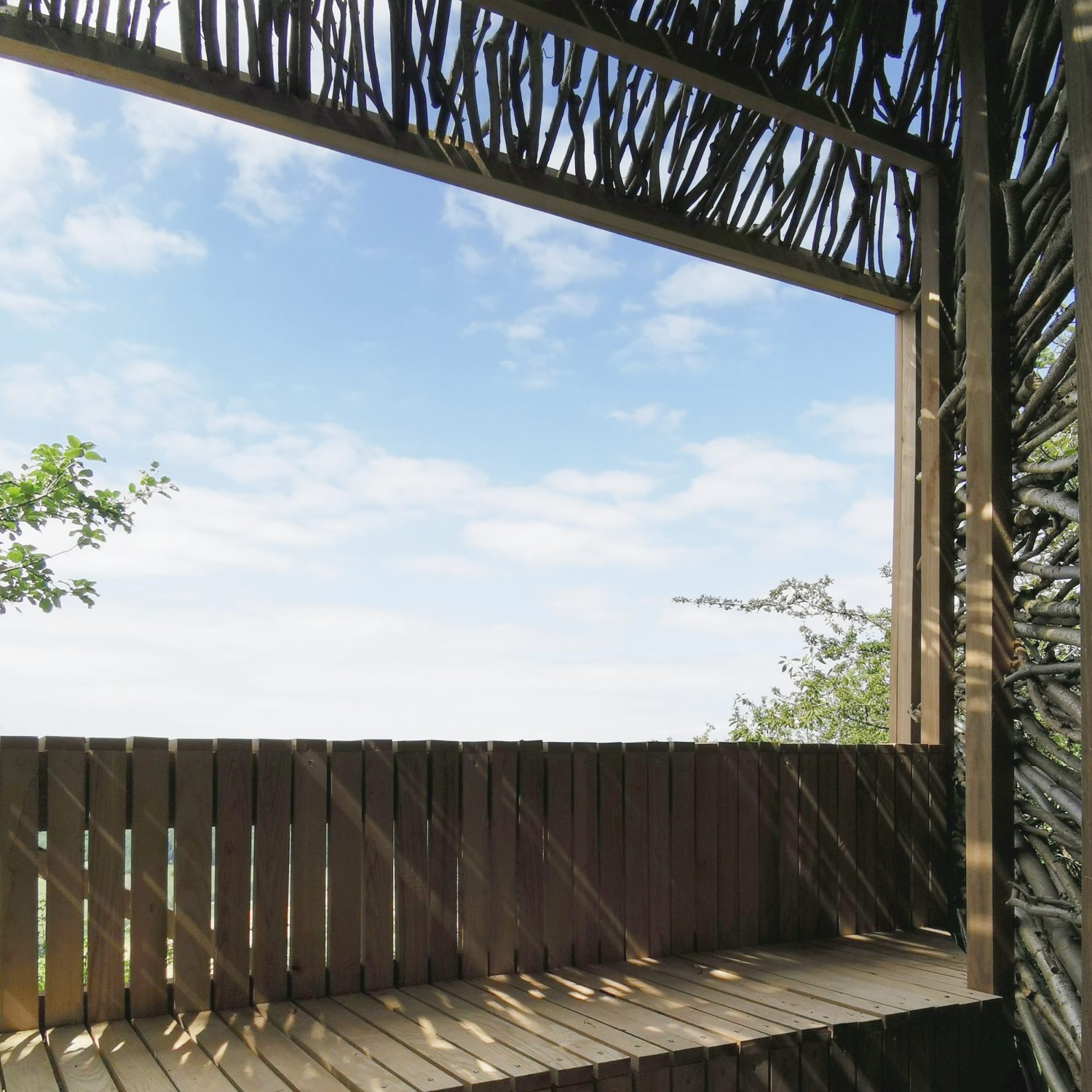 cababe en bois avec bardage en branches de noisetier et gradins amenant à un point de vue