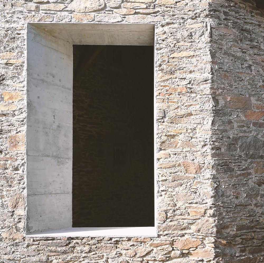Ouverture contemporaine en béton dans un mur en pierre