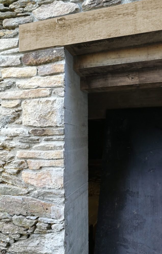 Ouverture contemporaine en béton dans un mur en pierre